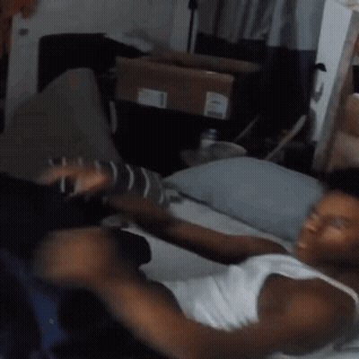 Man In White Tank Top Lying On Bed GIF