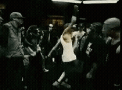 Man In White Tank Top Standing Before Crowd In Dark Room GIF