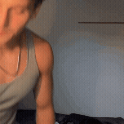 Man In White Tank Top Standing By Wall GIF