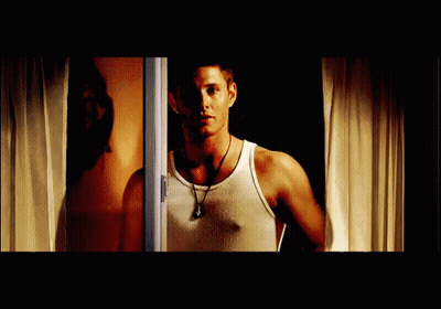 Man In White Tank Top Standing In Front Of Window GIF
