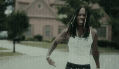 Man In White Tank Top Walking Down Street GIF