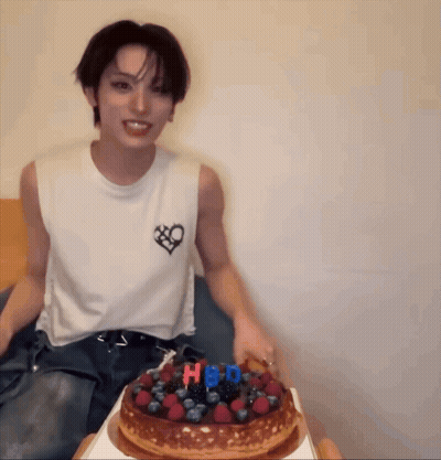 Man In White Tank Top With Heart Sitting Next To HBD Cake GIF