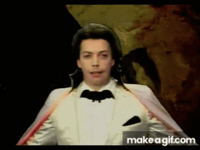 Man In White Tuxedo With Bat On Jacket GIF