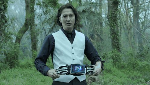 Man In White Vest Holding Device Saying Evil GIF