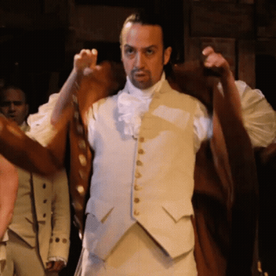 Hombre con chaleco blanco y botones dorados en una habitación oscura GIF