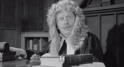 Man In Wig And Glasses Sitting At Table GIF