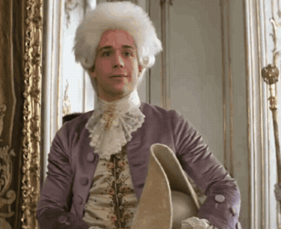 Man In Wig And Purple Jacket Holding Hat GIF