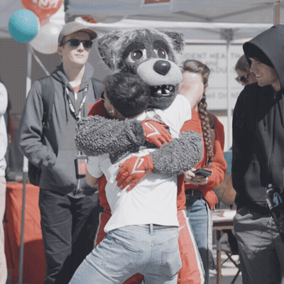 Man In Wolf Mascot Costume Hugs Another Man GIF