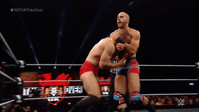 Man In Wrestling Ring With NXTUK Takeover Screen GIF