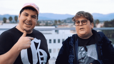 Man In Y T-Shirt Next To Man With Glasses GIF