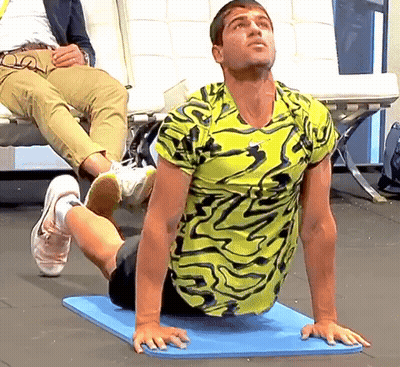 Man In Yellow And Black Shirt Stretching GIF