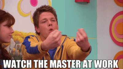 Man In Yellow And Blue Jacket Says Watch The Master At Work To Woman GIF