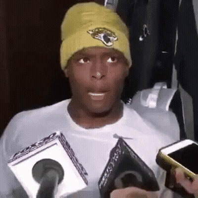 Man In Yellow Beanie Talking Into Microphone Holding Cell Phone GIF