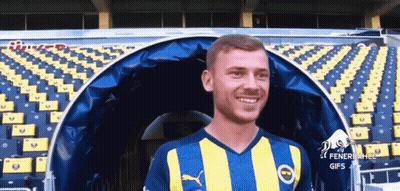 Man In Yellow Blue Striped Shirt Smiling In Stadium GIF