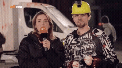 Man In Yellow Hard Hat Next To Woman With Microphone GIF