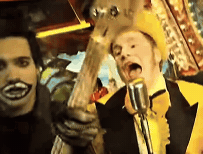 Man In Yellow Hat Singing Into Microphone Holding Guitar GIF