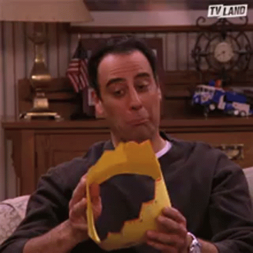 Man In Yellow Hat Sitting In Front Of TV Land Sign GIF