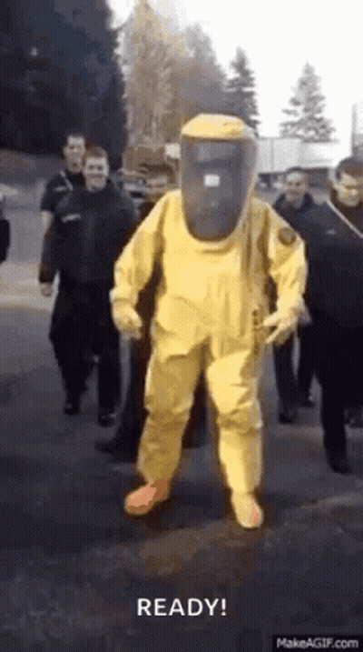 Man In Yellow Hazmat Suit Walking Street With Group GIF