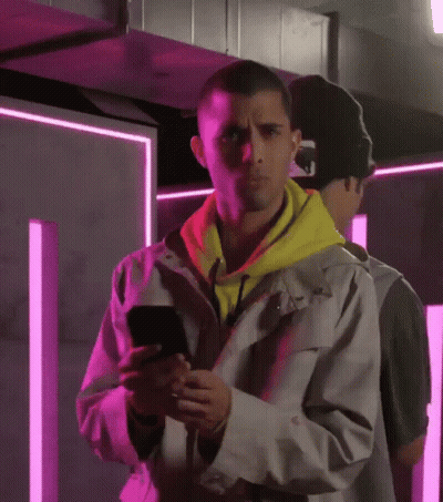 Man In Yellow Hoodie Looking At Phone GIF