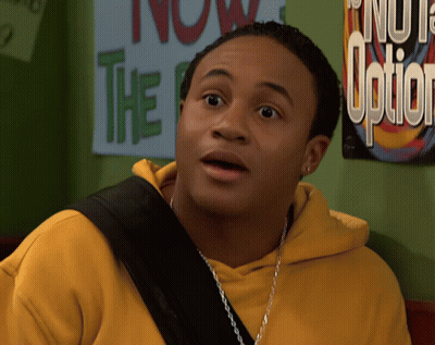 Man In Yellow Hoodie Standing In Front Of Sign Saying Now The Option GIF