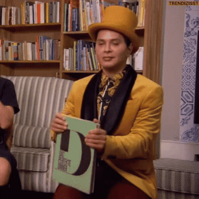 Man In Yellow Jacket And Top Hat Holding Book With Letter D GIF