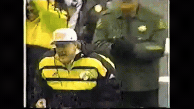 Man In Yellow Jacket And White Hat In Wheelchair In Front Of Crowd GIF