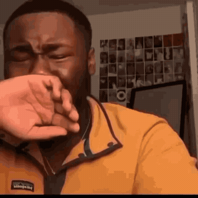 Man In Yellow Jacket Covering Face GIF