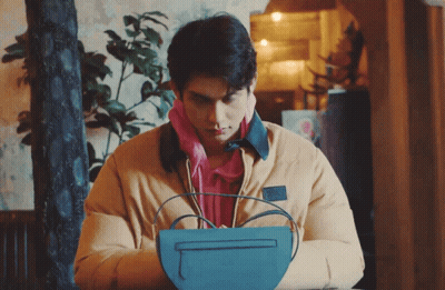 Man In Yellow Jacket Holding Blue Bag GIF