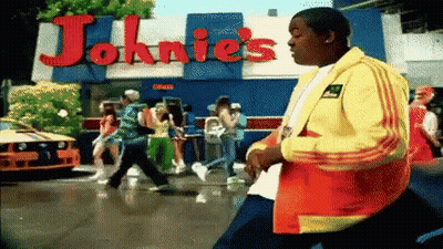 Man In Yellow Jacket In Front Of Johnnies GIF