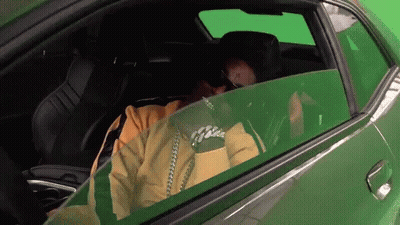 Man In Yellow Jacket In Green Car With Green Screen GIF
