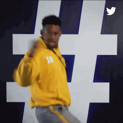 Man In Yellow Jacket Number 18 Dancing In Front Of Twitter Logo GIF