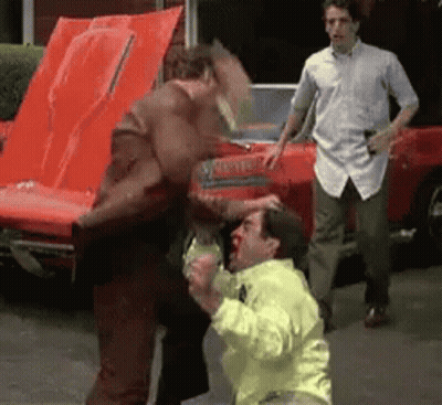Man In Yellow Jacket Punched By Man In Brown Jacket GIF