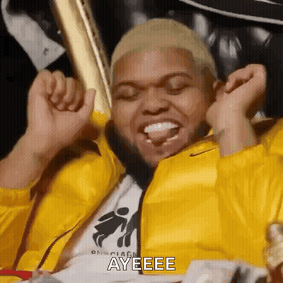 Man In Yellow Jacket Sitting On Couch Saying Ayeee GIF