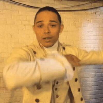 Man In Yellow Jacket Standing In Front Of Brick Wall GIF