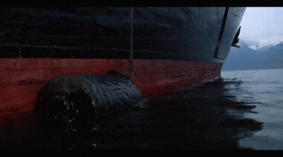 Man In Yellow Mask Holding Stick By Boat GIF
