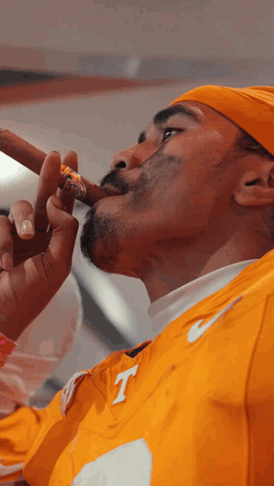 Man In Yellow Nike Shirt With Letter T Smoking Cigar GIF