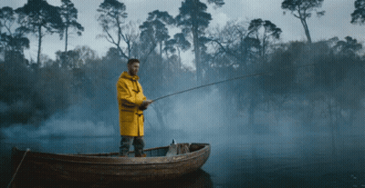 Man In Yellow Raincoat Fishing In Boat GIF