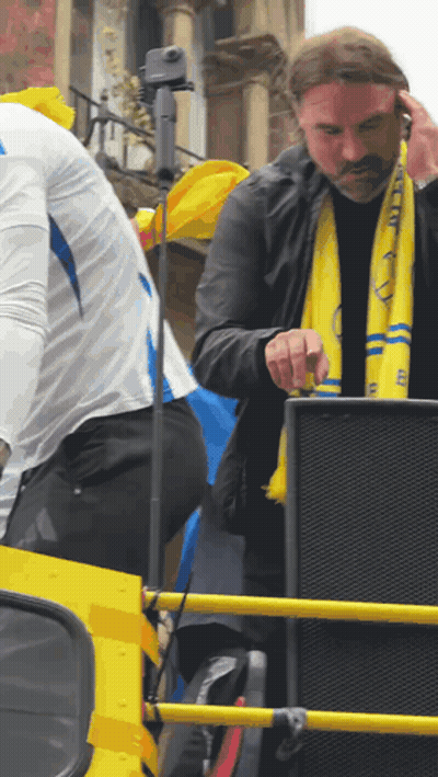 Man In Yellow Scarf With Letter E Standing In Front Of Speaker GIF