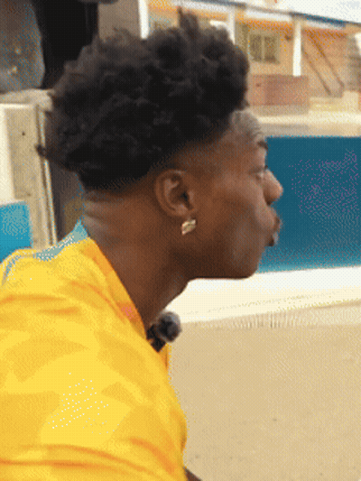 Man In Yellow Shirt And Earrings Looking Down GIF