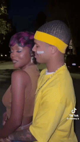 Man In Yellow Shirt And Headband Next To Woman With Purple Hair GIF