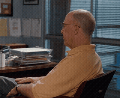 Man In Yellow Shirt At Desk With Stack Of Trays GIF