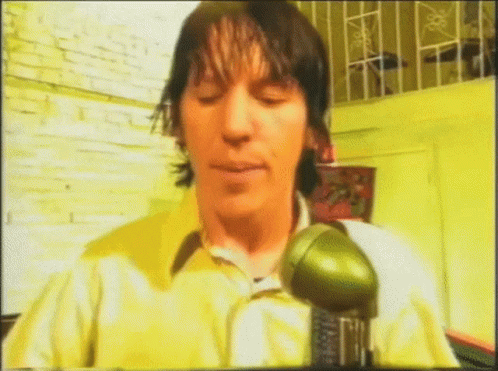 Man In Yellow Shirt Holding Green Object GIF