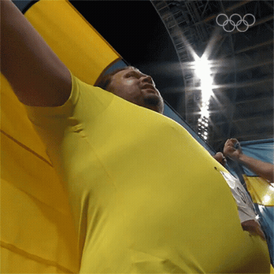 Man In Yellow Shirt Holding Olympics Flag GIF