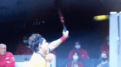 Man In Yellow Shirt Holding Tennis Racket At ITF Sign GIF