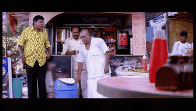 Man In Yellow Shirt In Front Of Coca Cola Machine GIF