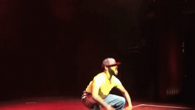 Man In Yellow Shirt Jumping With Arms Outstretched GIF