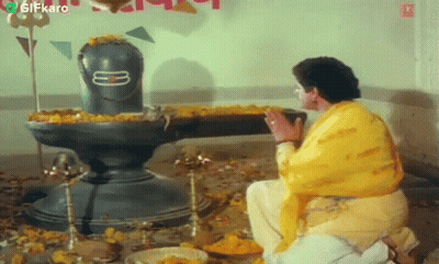 Man In Yellow Shirt Kneeling In Front Of Shiva Statue GIF