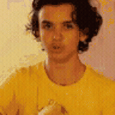 Man In Yellow Shirt Looking At Camera GIF