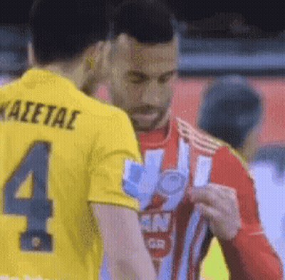 Man In Yellow Shirt Number 4 Talking To Man In Red Shirt GIF