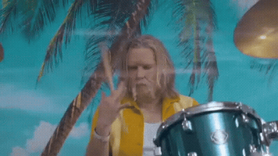 Man In Yellow Shirt Playing Drums In Front Of Palm Trees GIF